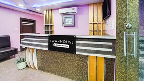 Una reception con una insegna che recita 'TOWNHOUSE Company Serviced', un condizionatore d'aria, un televisore a parete e una pianta in vaso.