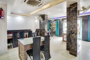 A conference room with a glass table, black chairs, a fire extinguisher, and a marble pillar.
