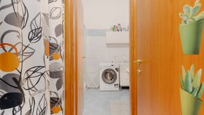 Ein Waschbereich mit Waschmaschine, Wäscheständer und Ablagefläche für Toilettenartikel.
