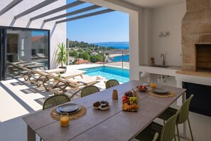 A dining area with a view of a swimming pool and a mountain landscape. - NEW! Discover Villa Logos: Your Seaview Retreat in Croatia (Dugi Rat)