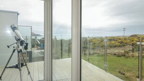 A telescope on a balcony with a view of a coastal landscape. - Portnablagh Cottage (Portnablagh)