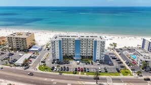 Un hotel con estacionamiento, piscina y vistas a la playa y al océano.