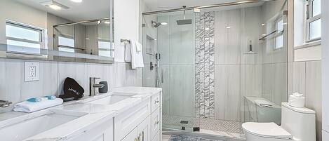 Une salle de bain moderne avec une douche à parois de verre, des toilettes blanches et un meuble-lavabo en marbre.