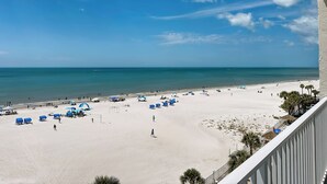 Una playa con cielo despejado, orilla arenosa y algunas sombrillas.