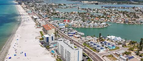 An aerial view of a coastal city with a beach, marina, and residential buildings.