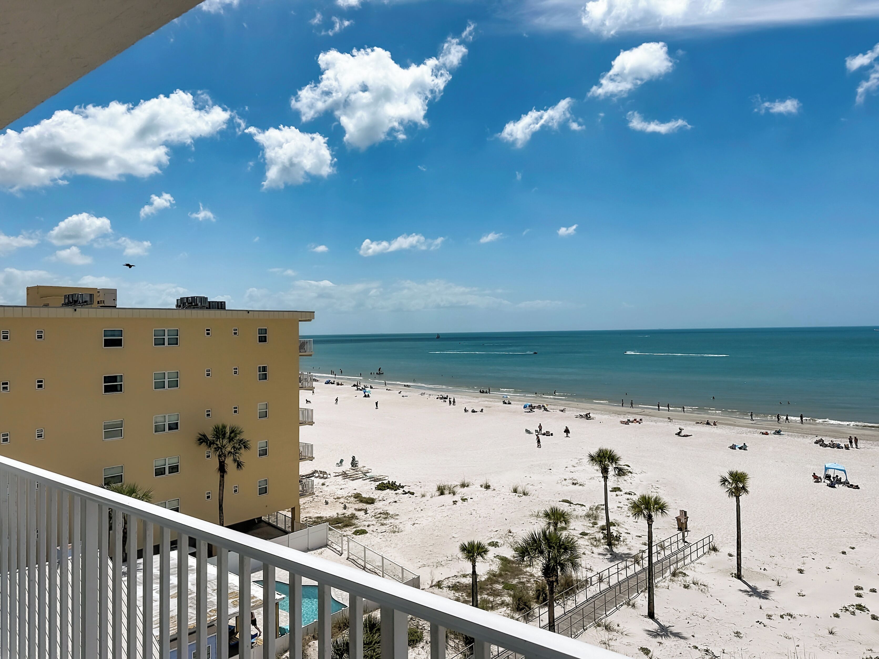Vista sulla spiaggia con un edificio in primo piano, cielo sereno e mare calmo.