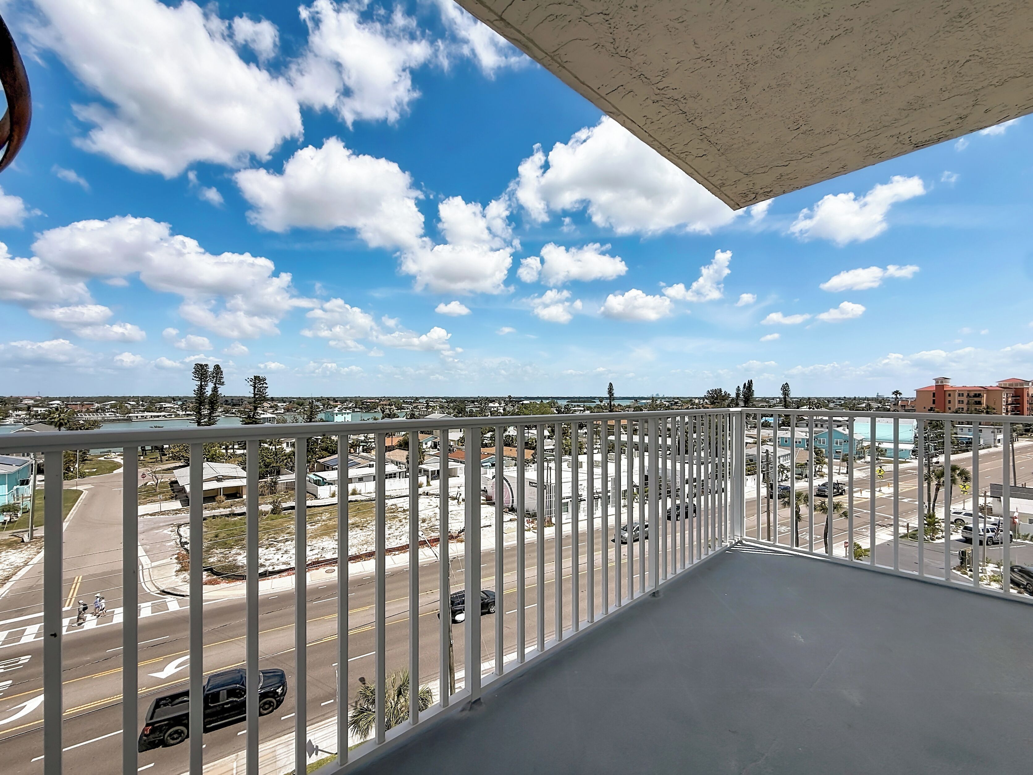 A balcony with a view of a cityscape, including roads and buildings.