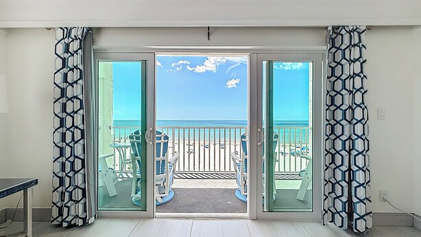 Una habitación con vistas a la playa, un balcón con sillas y una mesa.