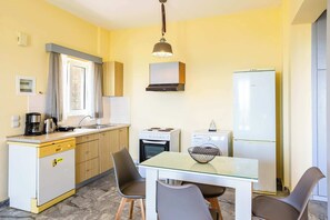 A compact kitchen with a dishwasher, stove, refrigerator, and a dining table with chairs. - Beachfront Nest Memi, Koroni-Seaheaven House A1 (Koroni)