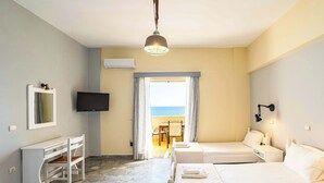 Habitació d'hotel amb un llit, un escriptori, una televisió i vista al mar.