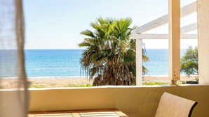 Un balcó amb vista al mar, una palmera i una taula de fusta.