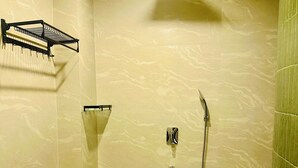Une salle de bain avec une douche, un porte-serviettes et des toilettes.