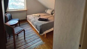 Ein Schlafzimmer mit einem Bett, einem Sessel, einem Fenster und einer Tür.