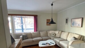Ein Wohnzimmer mit Sofa, Couchtisch, Pendelleuchte und Heizkörper.