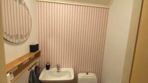 Ein kleines Badezimmer mit einem weißen Waschbecken, einer Toilette und einem Spiegel an der Wand.