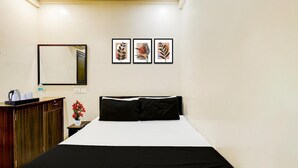 Habitación de hotel con una cama, un armario de madera, un espejo y tres cuadros en la pared.