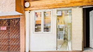 Una entrada de edificio con una reja de metal, puerta corredera de vidrio y piso de madera.