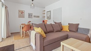 A modern living room with a sofa, coffee table, and dining area. - Bed & Breakfast «Pomme reinette» – Shared Pool, Wi-Fi & Air Conditioning (Le Val)