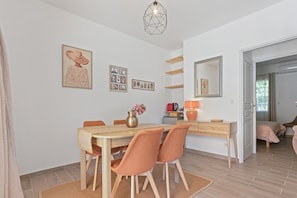 Un coin repas avec une table en bois, des chaises, un vase de fleurs et des œuvres d’art murales.
