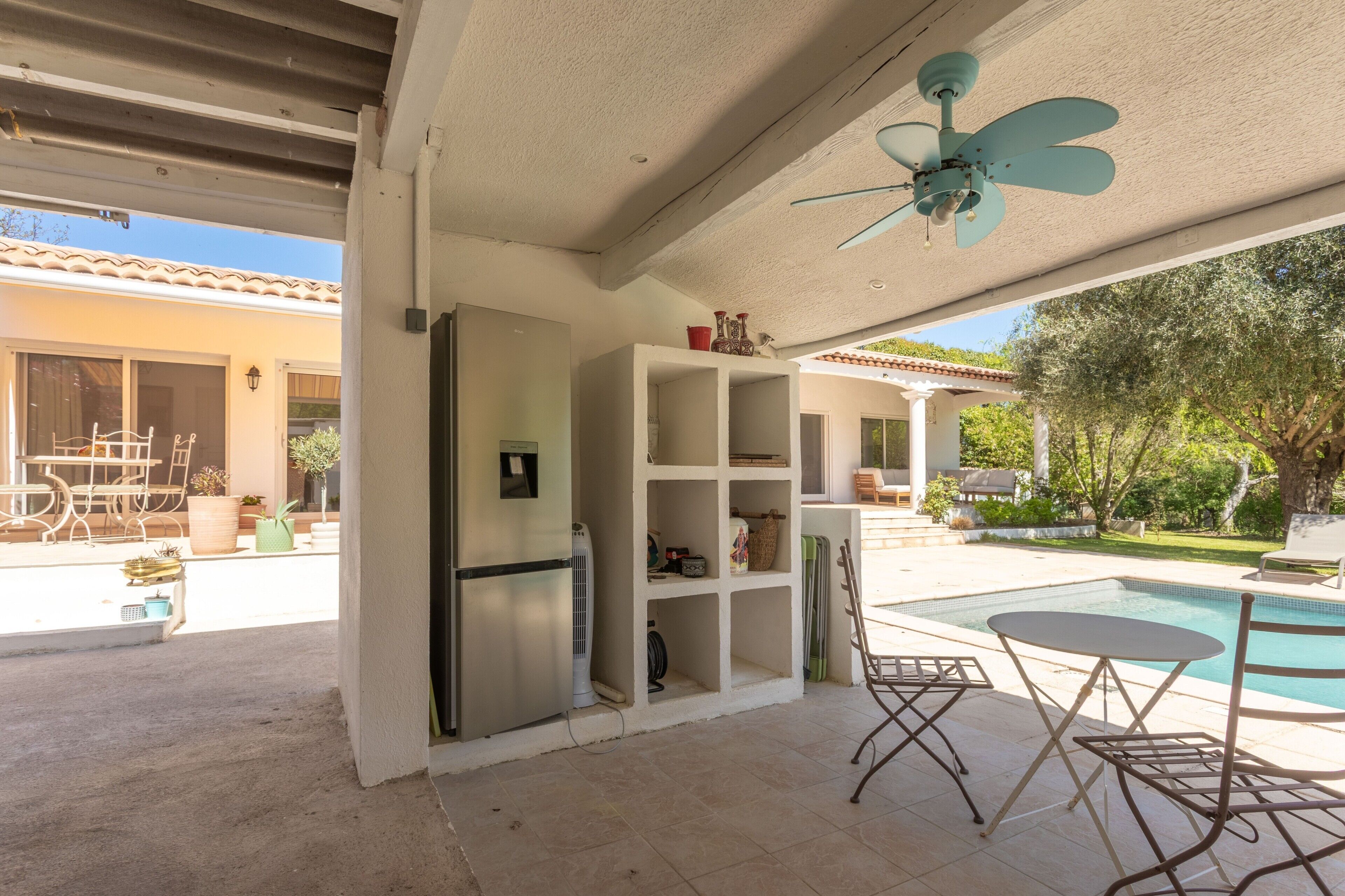 Un portico coperto con una ventola a soffitto, una piscina e mobili da esterno.