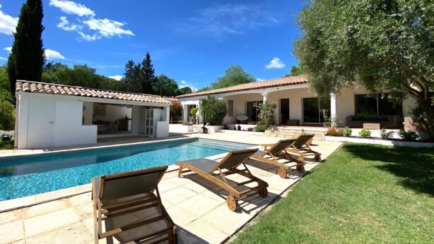 A pool area with lounge chairs, a covered patio, and a building with a tiled roof. - Bed & Breakfast «Pomme reinette» – Shared Pool, Wi-Fi & Air Conditioning (Le Val)