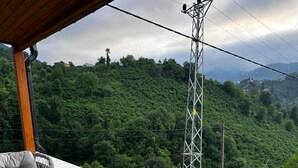 Eine Terrasse mit Korbmöbeln und einem Glastisch, mit Blick auf eine üppige grüne Landschaft.