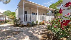 A two-story building with a covered porch, a gravel driveway, and surrounding vegetation. - Jesolo Family Resort (Jesolo)