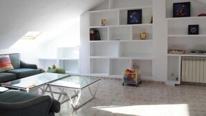 Een woonkamer met een glazen salontafel, een bank, een boekenkast en een radiator.
