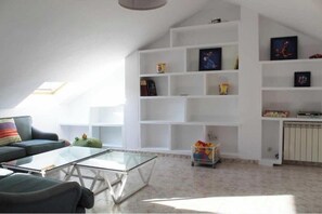 A living room with a glass coffee table, a sofa, a bookshelf, and a radiator. - VACATIONS IN MARESME HOUSE FOR 7 PEOPLE (El Masnou)