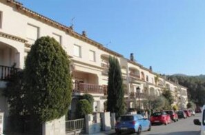 A row of residential buildings with balconies, parked cars, and greenery. - VACATIONS IN MARESME HOUSE FOR 7 PEOPLE (El Masnou)