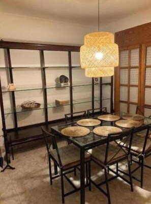 A dining area with a glass-top table, black chairs, and a woven light fixture. - VACATIONS IN MARESME HOUSE FOR 7 PEOPLE (El Masnou)