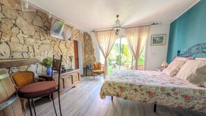 Een slaapkamer met een bed, een stoel, een tafel, een stenen muur en een raam.