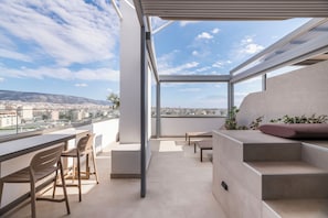 Ein moderner Balkon mit Blick auf die Stadt, eine Sitzecke mit Kissen und ein Essbereich.