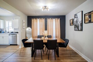 A dining area with a wooden table, black chairs, and a vase with dried flowers.