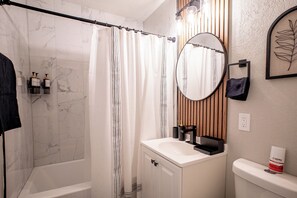A bathroom with a shower, a sink, a mirror, and a toilet.