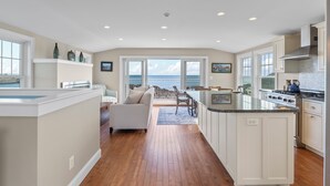 A spacious kitchen with a large island, a dining area with a view, and a living room with a sofa and a view.