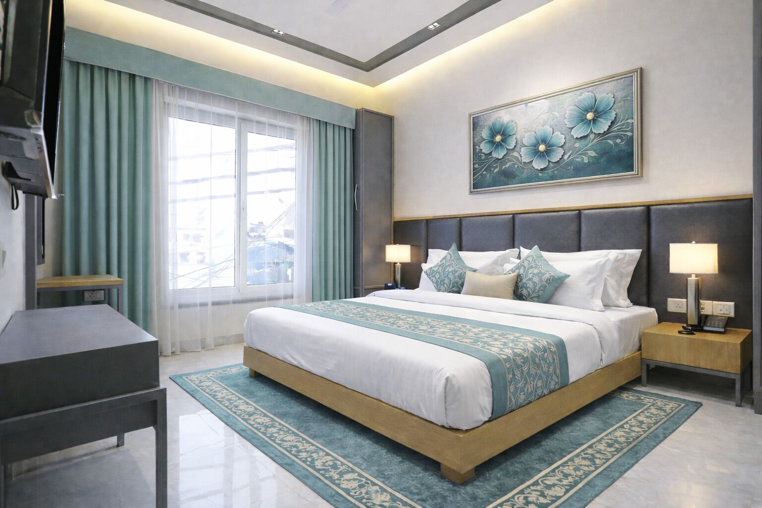 A hotel room with a large bed, bedside lamps, a desk, and a painting on the wall.