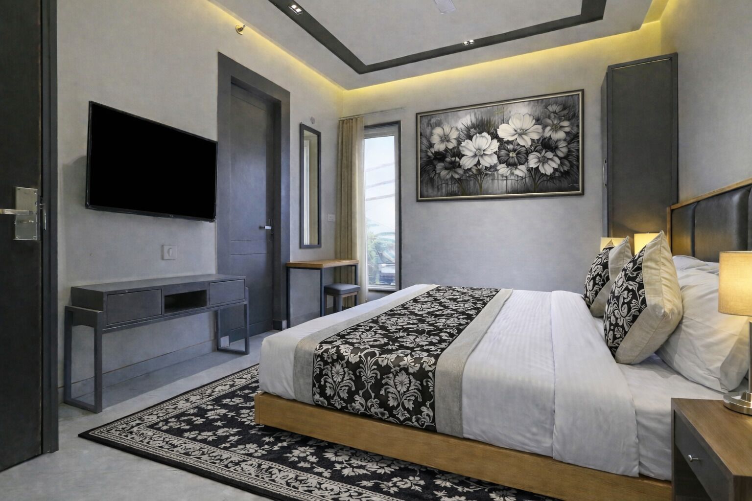 A modern bedroom with a large bed, a flat-screen TV, a desk, and a painting on the wall.
