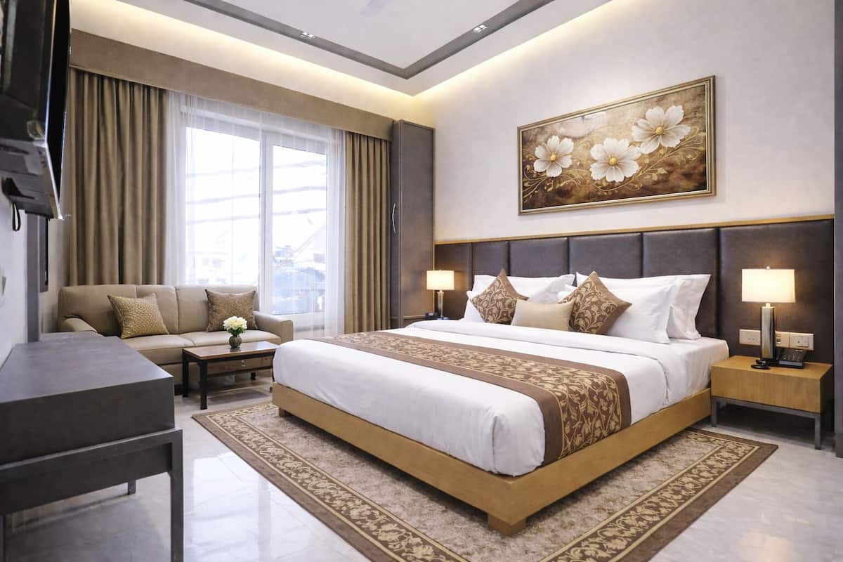Ein Hotelzimmer mit einem großen Bett, einer Schlafcouch, einem Schreibtisch und einem Fernseher.