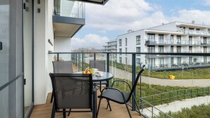 A balcony with a table, chairs, and a fruit bowl. - Stylish Apartment | Balcony, Parking, Wellness Area (Dziwnów)