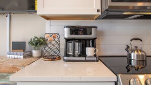 Eine Küche mit Kaffeemaschine, Wasserkocher und einer Tasse Kaffee auf der Arbeitsfläche.