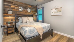 Ein Schlafzimmer mit Bett, Holzvertäfelung, Deckenventilator, Nachttisch, Lampe und einer Karte an der Wand.