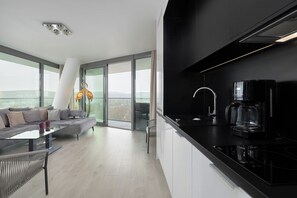 Eine moderne Küche mit schwarzem Arbeitsplatz, einer Kaffeemaschine und einer Glastür zum Balkon.