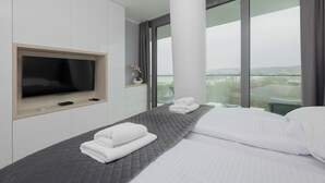 Ett modernt hotellrum med en stor säng, en platt-TV och utsikt över staden.