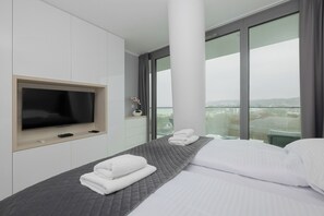 Ein modernes Hotelzimmer mit einem großen Bett, einem Flachbildfernseher und Blick auf die Stadt.