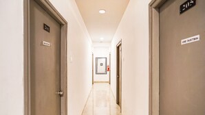 Un couloir d’hôtel avec des portes portant les numéros « 2011 » et « 205 », un extincteur et un panneau indiquant qu’il faut utiliser la poubelle.