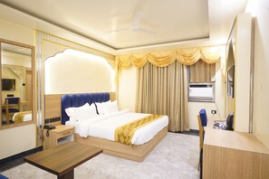Una camera d'albergo con un letto, un comodino, una scrivania, una sedia e un grande specchio.
