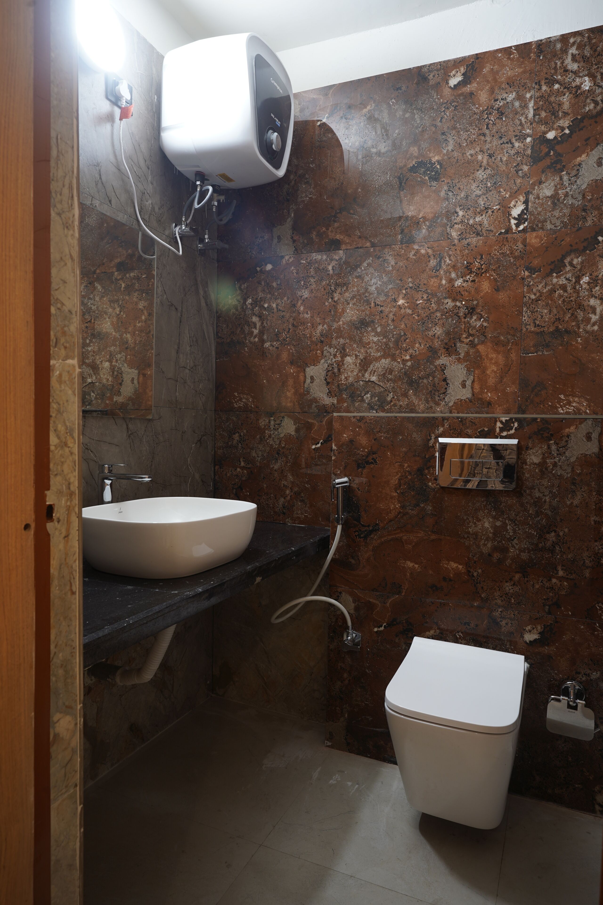 A bathroom with a sink, toilet, and a hand dryer mounted on the wall.