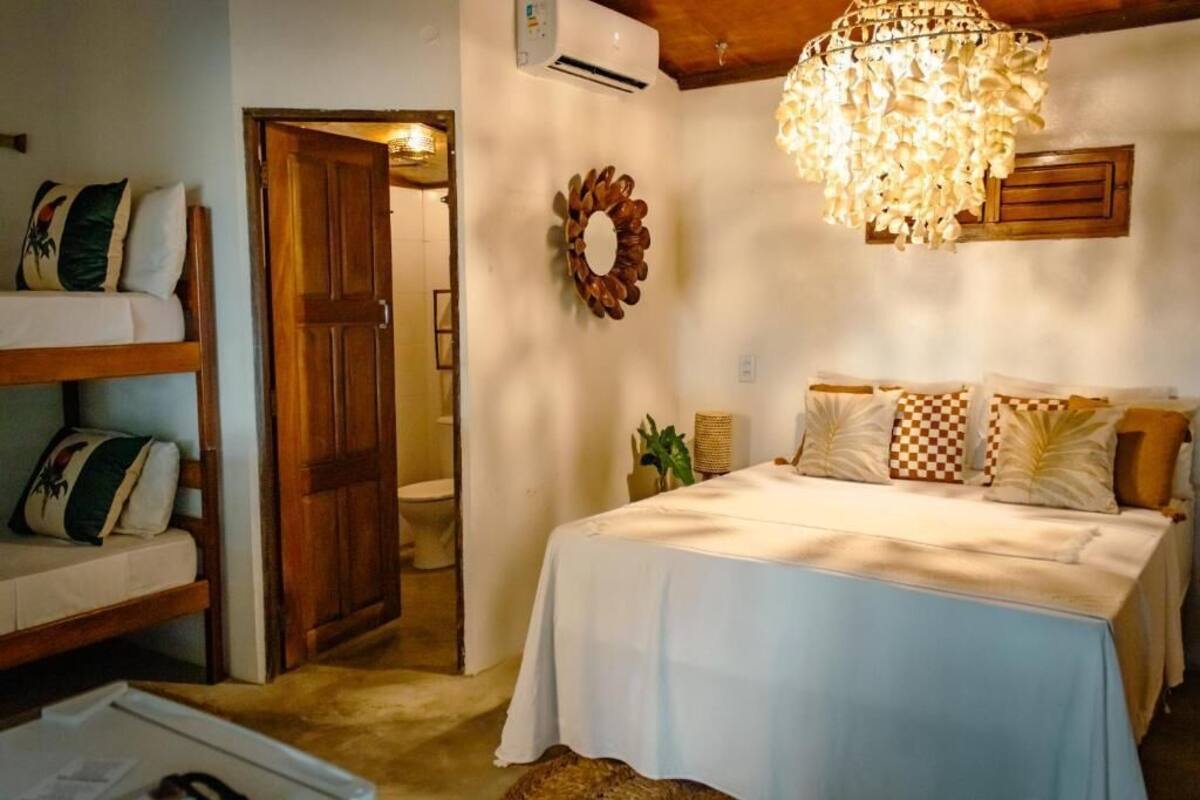 Un dormitorio con una cama, una puerta de madera, aire acondicionado de pared, un candelabro y un adorno mural.