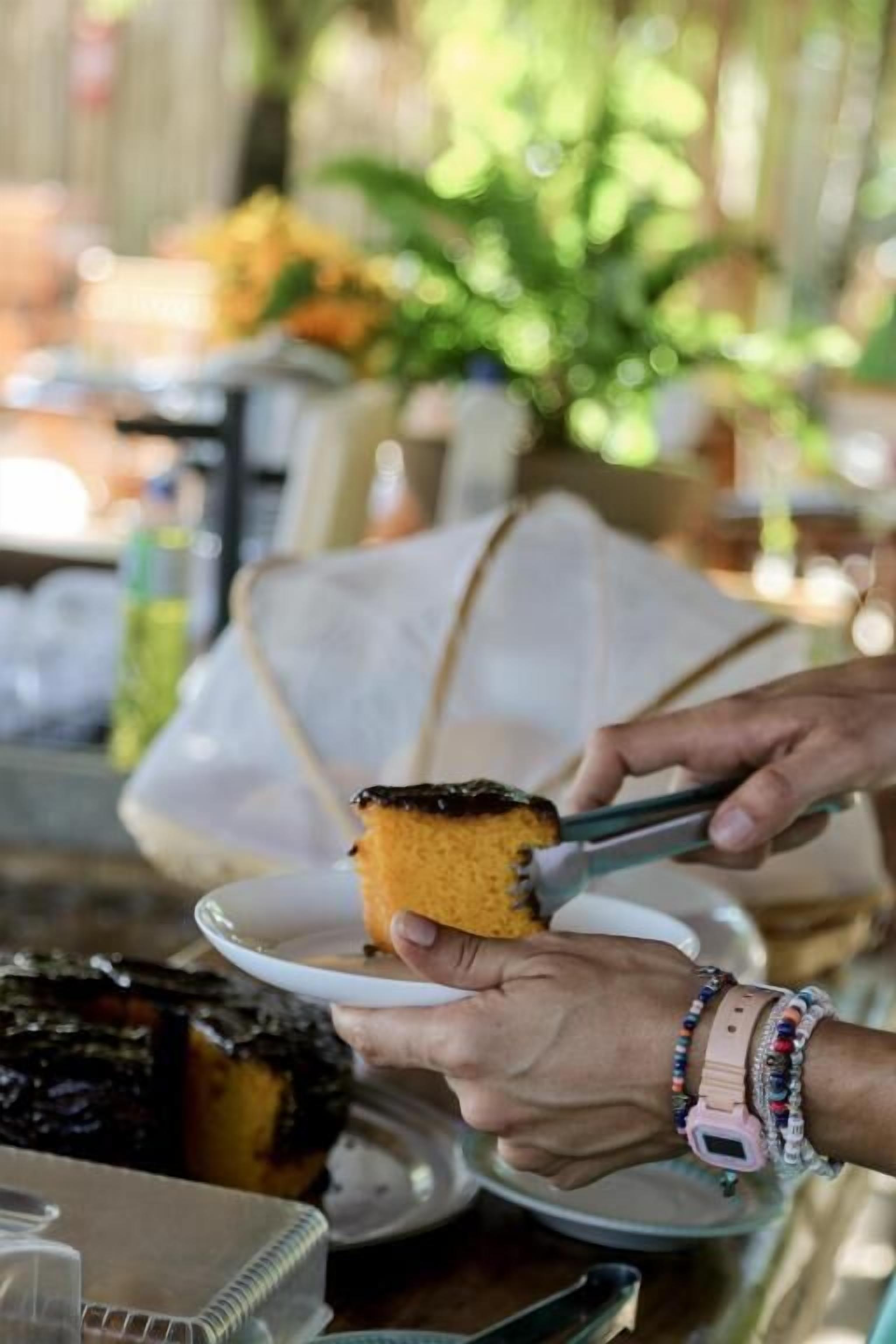 Manos cortando un pastel con un cuchillo sobre un plato.